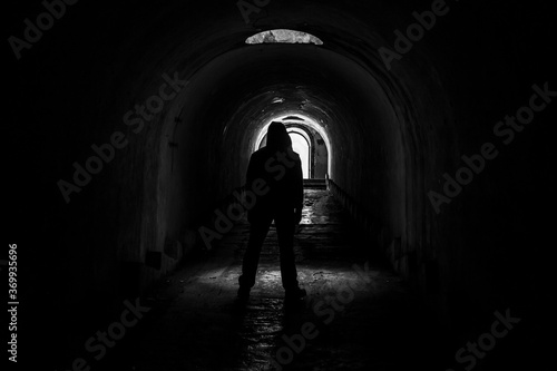 A lonely hooded man walks out into the light from a dark  abandoned underground corridor in fort Pospelova  Vladivostok.