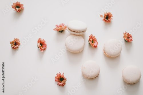 Fototapeta Naklejka Na Ścianę i Meble -  Trendy design with macaroons and flowers on white background. top view.  Place for text. Birthday, wedding card