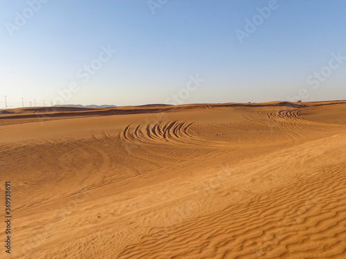 Sand dunes in the desert with tire traces on surface