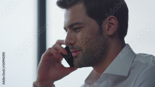 Businessman talking on smartphone in office. Man calling on cellphone