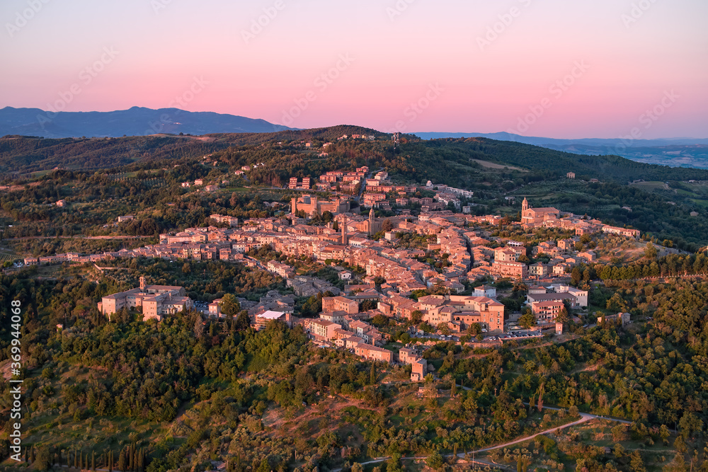 Obraz premium Aerial view of a Montalcino city, illuminated by sunrise. Ancient city standing on hilly landscape of a typical Tuscany countryside. Italy.