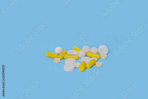 a lot of white and yellow pills on a blue background