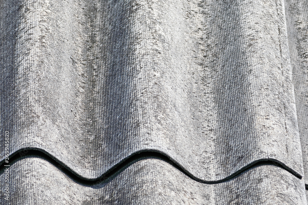 Roof texture. A fragment of an old roof made of wave slate sheets in close-up.