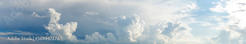 Epic panoramic cloudscape. Horizontal banner clouds with dark blue storm on the left and white fluffly sunny clouds on the right. Beautiful sky that can be used as background.                      