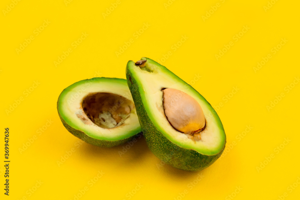 Cut fresh ripe avocado on yellow background.