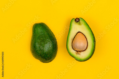 Cut fresh ripe avocado on yellow background.