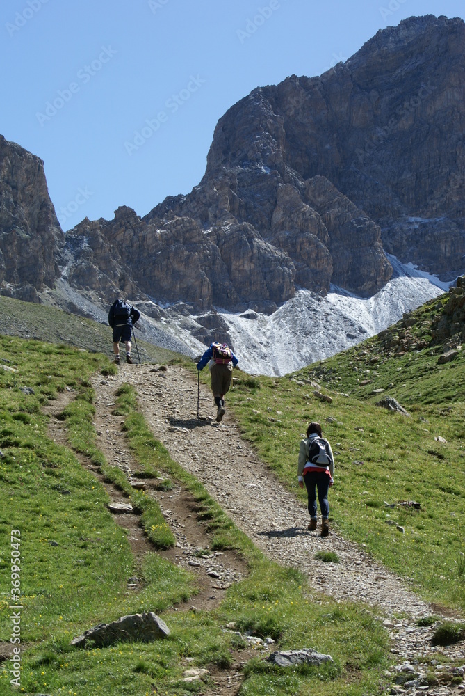 Three people hiking in the mountains in Roburent, Italy