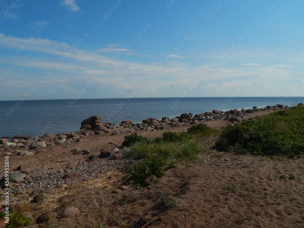 Nice view: sandy seashore, stones, horizon and blue sky