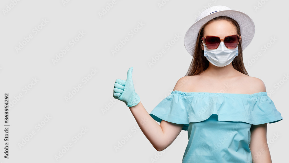 Health protection. COVID-19 prevention. Woman in medicine mask and gloves showing thumb up. Isolated on gray copy space. Quarantine measures. Summer tours Health protection. COVID-19 prevention. Woman in medicine mask and gloves showing thumb up. Isolated on gray copy space. Quarantine measures. Summer tours