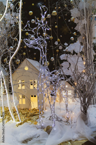 Christmas and new year decorations in the form of a glowing deer. Garlands, Christmas tree, toy houses. © Olga