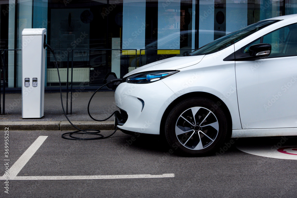 Modern electric car plugged in charging on the street station. New energy vehicles, environment friendly alternative energy for cars