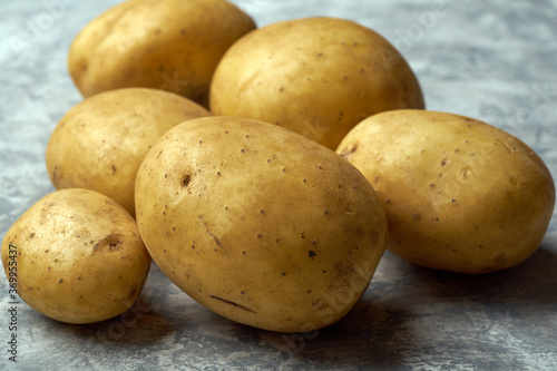 Fresh raw potatoes on textured background