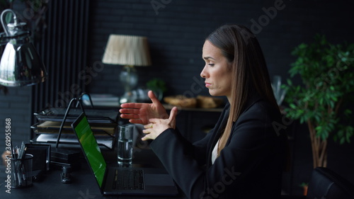 Successful businesswoman calling video online on laptop with green screen