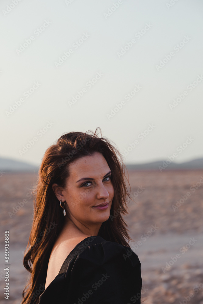 dark haired European woman in a black dress in the countryside