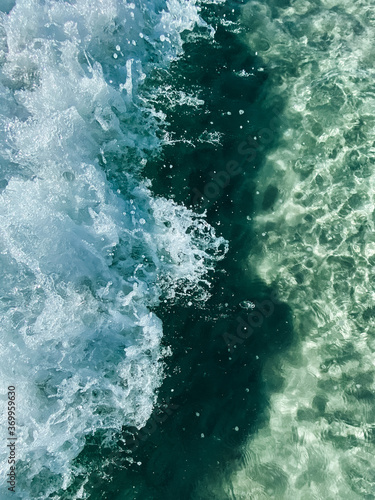 Small waves on the transparent clear water of the sea. White sea foam