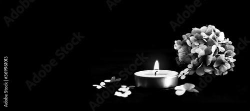 Fotografie Condolence card with candle and  flowers isolated on black background with copy