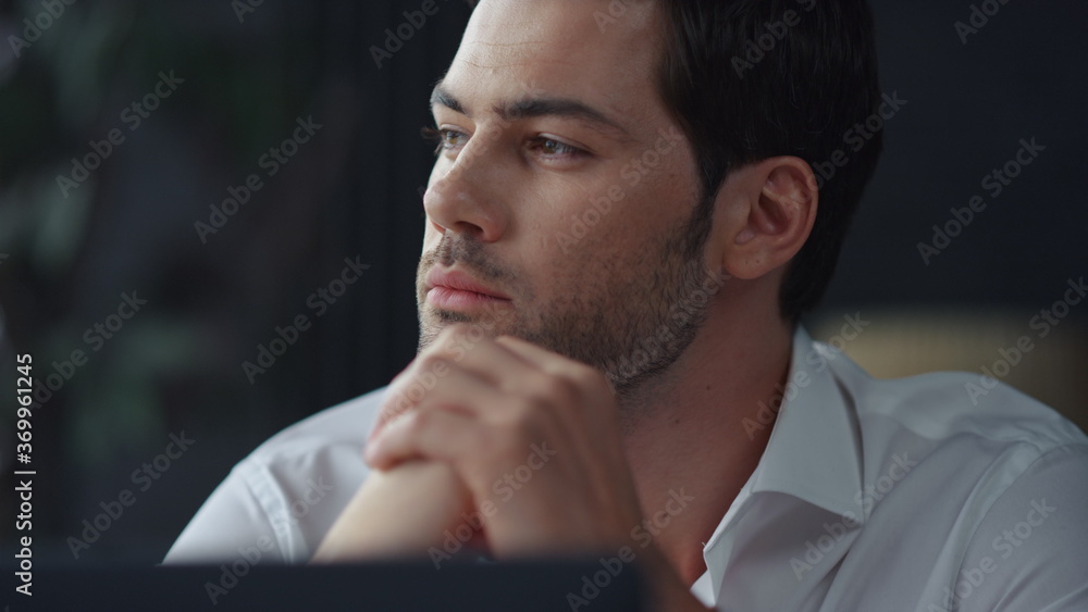 Thoughtful businessman sitting at remote workplace with laptop computer Thoughtful businessman sitting at remote workplace with laptop computer