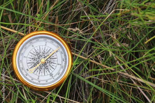 round compass on background of summer grass as symbol of tourism with compass, travel with compass and outdoor activities with compass