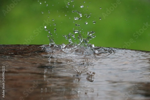 rain is falling in a wooden table full of water in the garden 