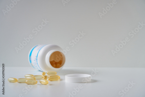 Omega 3 fish oil capsules spilled from a plastic bottle. Medical food supplements. Unsaturated fatty acid.