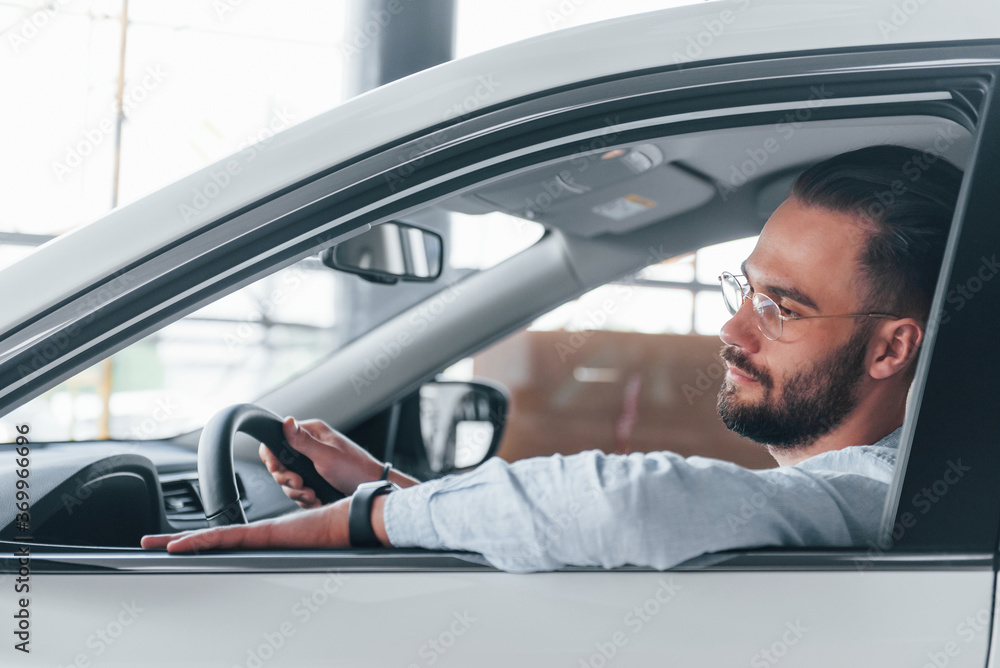 Young handsome man in formal clothes sitting in brand new automobile