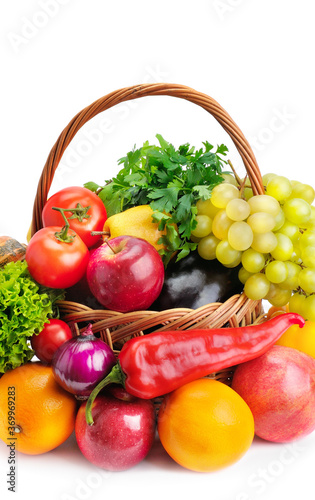 Composition with vegetables and fruits in wicker basket isolated on white. Vertical photo.