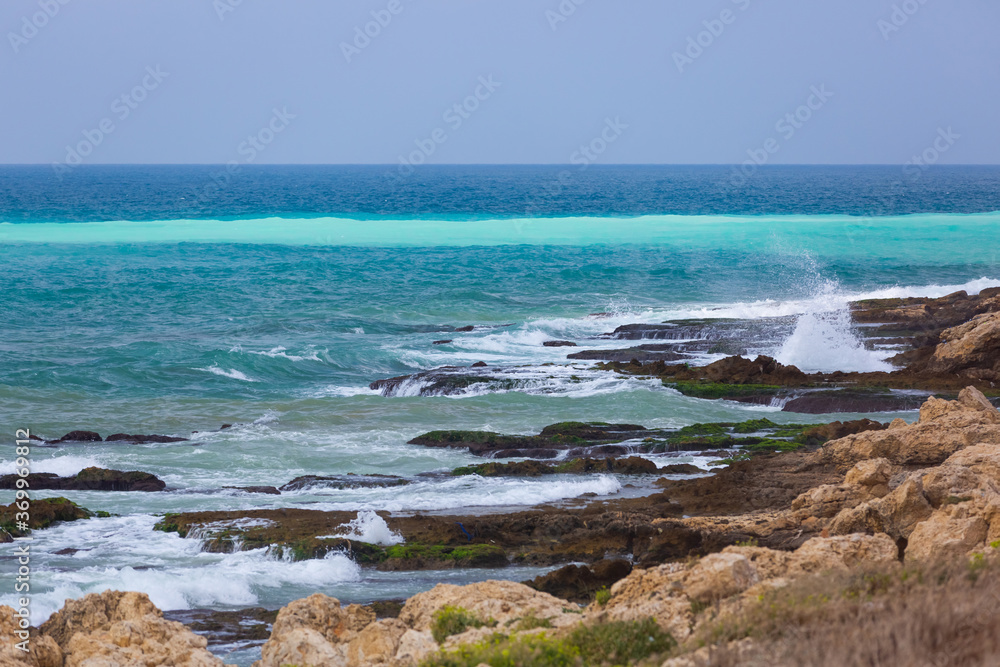 Amazing turquoise waves and white foam. Waves crashing on the rocky coast of Lebanon. Blue sea water. A vibrant seascape with stone beach. Lebanese Mediterranean coastline Amazing turquoise waves and white foam. Waves crashing on the rocky coast of Lebanon. Blue sea water. A vibrant seascape with stone beach. Lebanese Mediterranean coastline