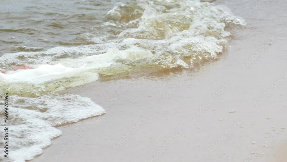 White plastic bag floating in sea water on sandy beach shore White plastic bag floating in sea water on sandy beach shore