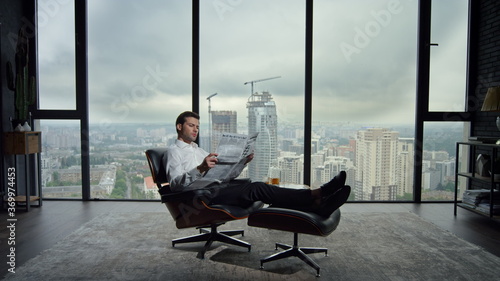 Businessman holding open newspaper in office. Worker reading financial newspaper