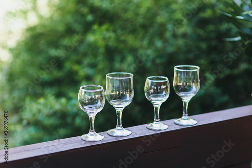 Empty glass glasses for champagne, wines are in a row on a wooden rack in nature.