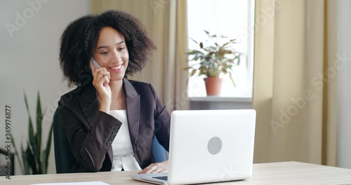 Young friendly business woman consultant wearing blazer jacket, sitting in cozy office at home, talking on mobile phone line, speaking negotiating, discussing with people, answering call positivly photo