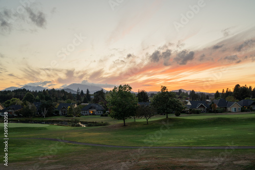 An Oregon sunset at a green golf course with mountains in the distance