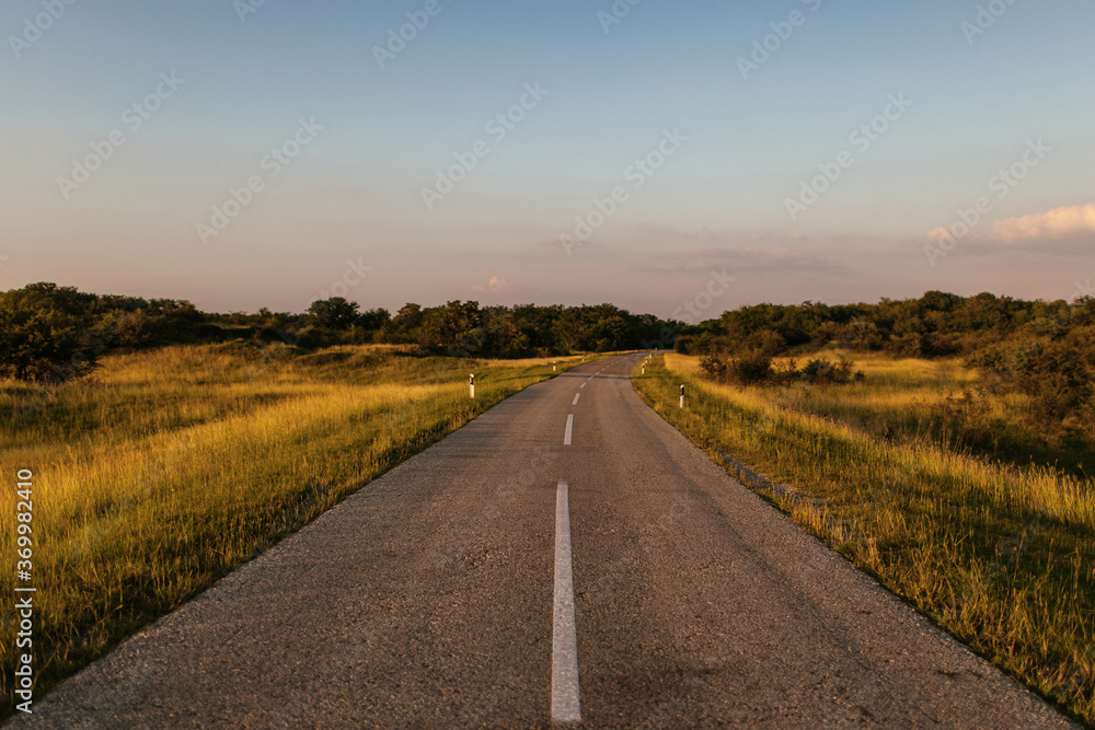 Landscape of a golden field and country road at sunset Landscape of a golden field and country road at sunset