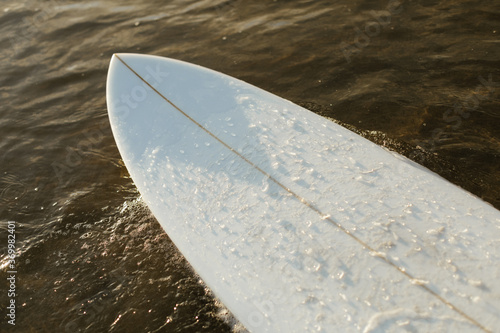 nose of surfboard on surface of water photo