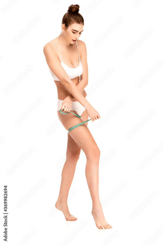 barefoot woman in top and panties measuring thigh isolated on white barefoot woman in top and panties measuring thigh isolated on white