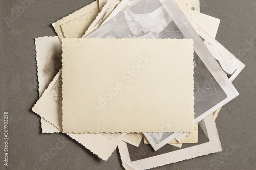 An old faded photo on a stack of old photos on a black page in an old photo album. Copy space, minimal style, the concept of storing memories.