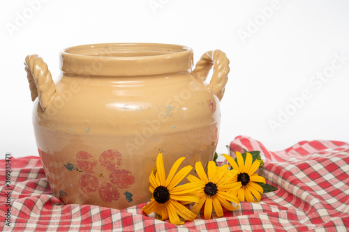 Fotografie Antique crock sitting in red and white table cloth with black-eyed susans