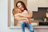 On the kitchen. Young mother with her little daughter in casual clothes together indoors at home