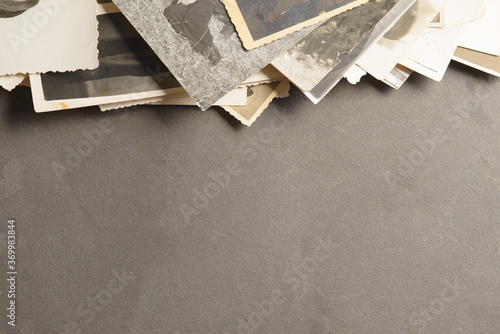 A stack of old photos on a black page in an old photo album. Copy space, minimal style, the concept of storing memories.