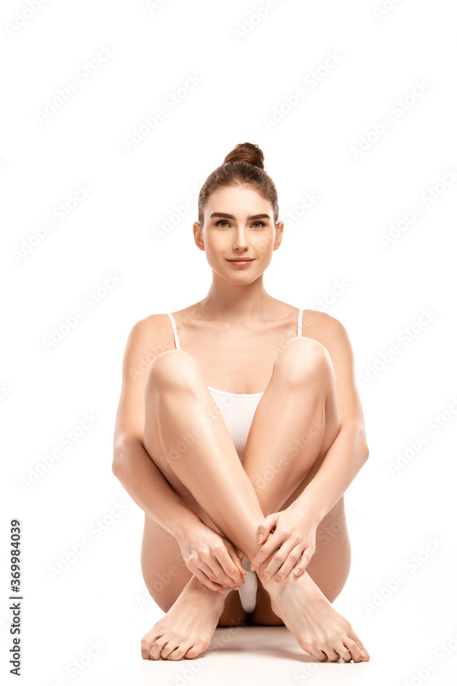 young woman in bodysuit sitting with crossed legs on white young woman in bodysuit sitting with crossed legs on white
