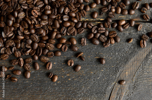 Roasted arabica coffee beans scattered on a wooden table. Fresh coffee beans.