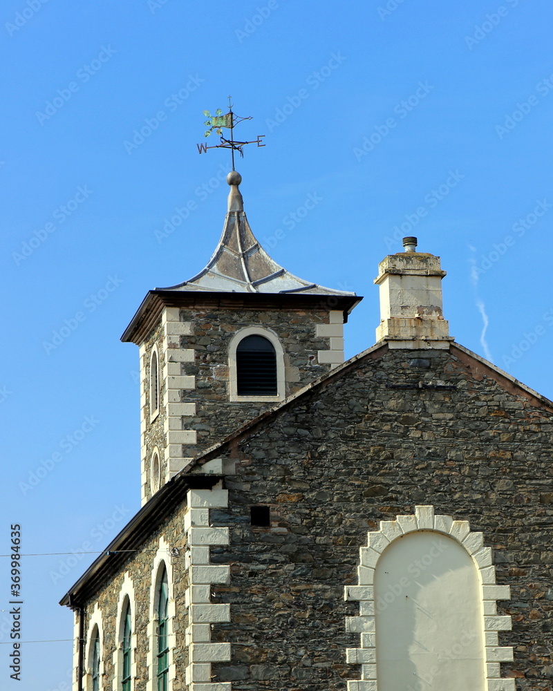 Old rustic stone church or chapel exterior with weather vane