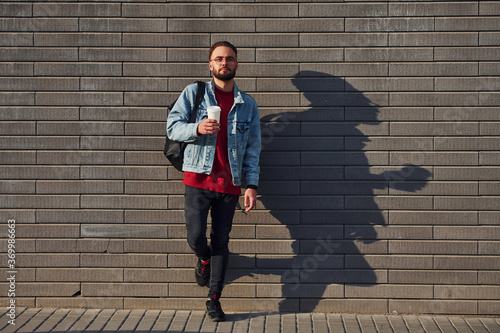 Handsome young guy in casual clothes is outdoors at sunny daytime