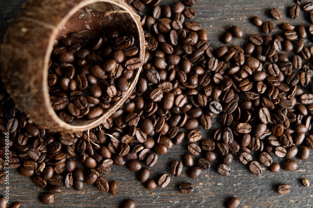 Roasted arabica coffee beans scattered on a wooden table from a coconut. Fresh coffee beans. Roasted arabica coffee beans scattered on a wooden table from a coconut. Fresh coffee beans.
