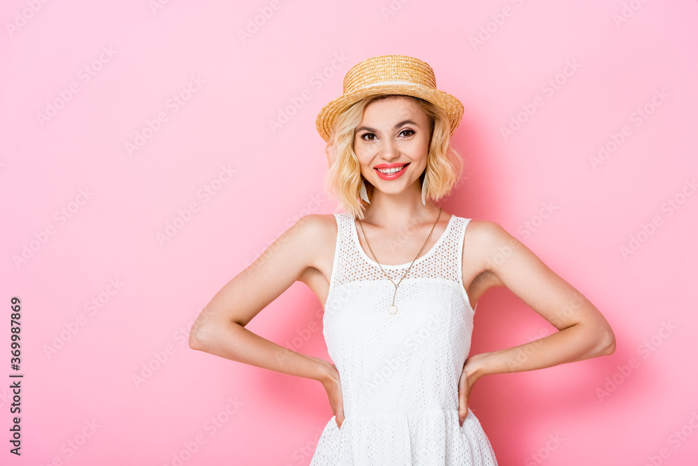 young woman in straw hat standing with hands on hips on pink young woman in straw hat standing with hands on hips on pink