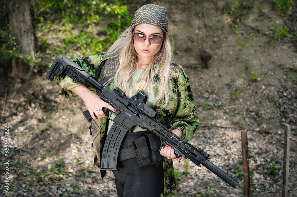 Attractive female army soldier hold rifle machine gun. Woman with weapon. Firearm outdoor shooting range