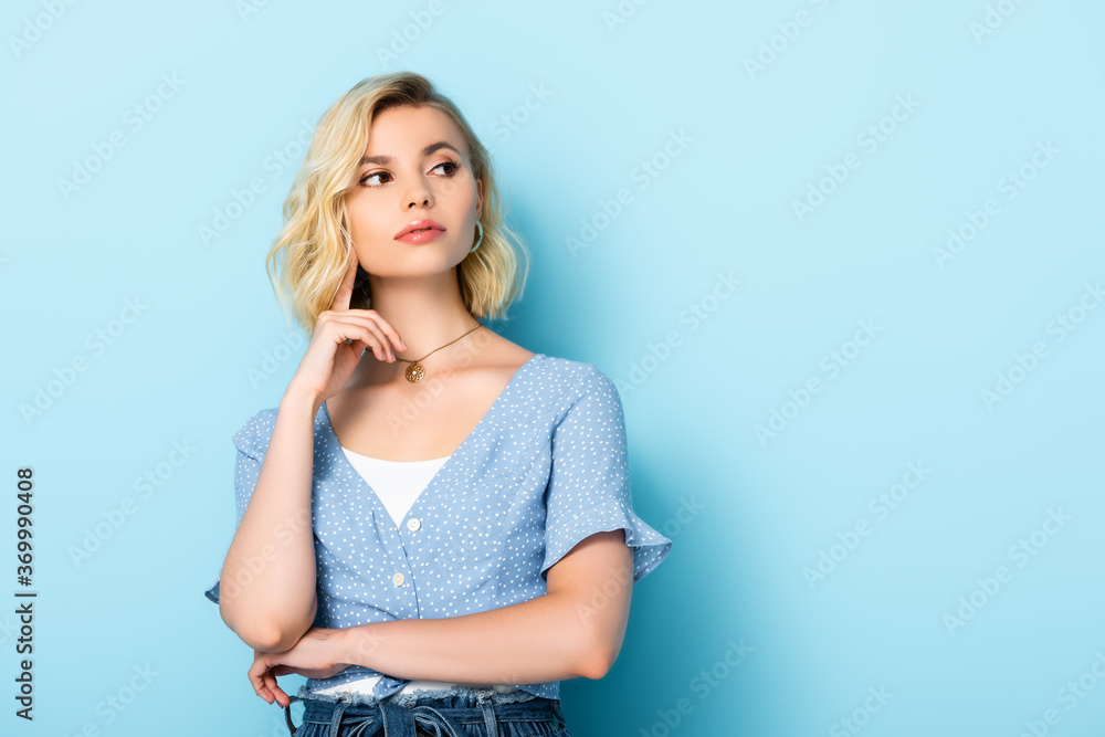 pensive young woman looking away and standing on blue pensive young woman looking away and standing on blue