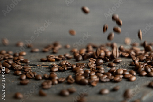 Roasted arabica coffee beans falling on a wooden table. Fresh coffee beans.