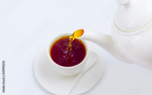 tea is poured into a white Cup from a white teapot on a white background