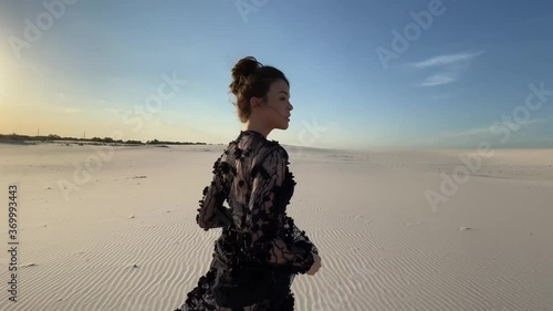 Woman in lace black dress runs in desert. photo